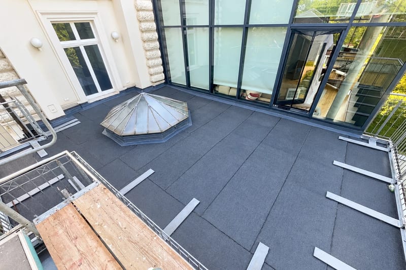 Dachterrasse mit neuer bituminöser Abdichtung, achteckige Lichtkuppel und bodentiefe Fenster, seitlich ein Gerüst